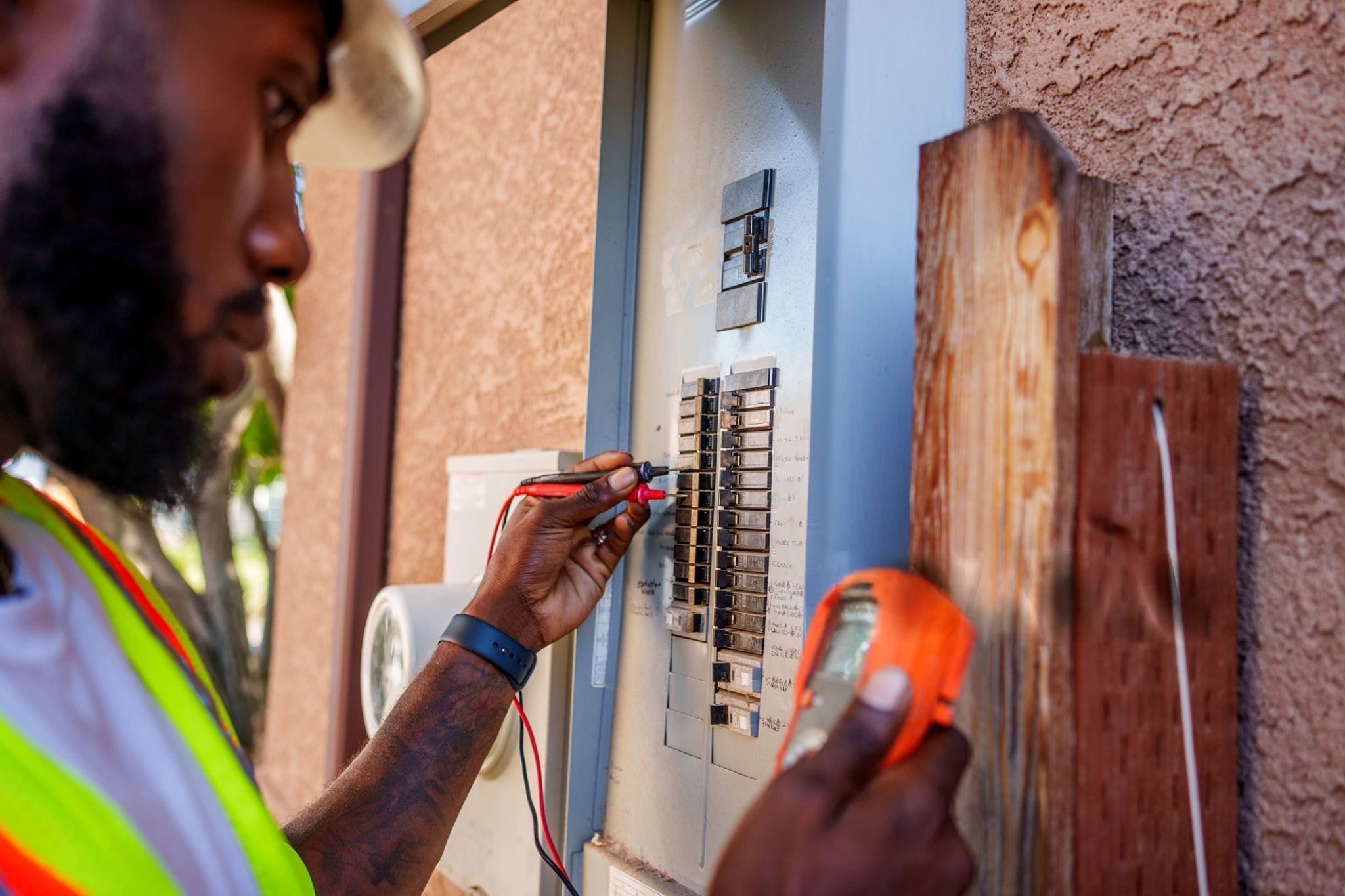 An electrician testing circuits in a hand-labelled residential panel on a service call