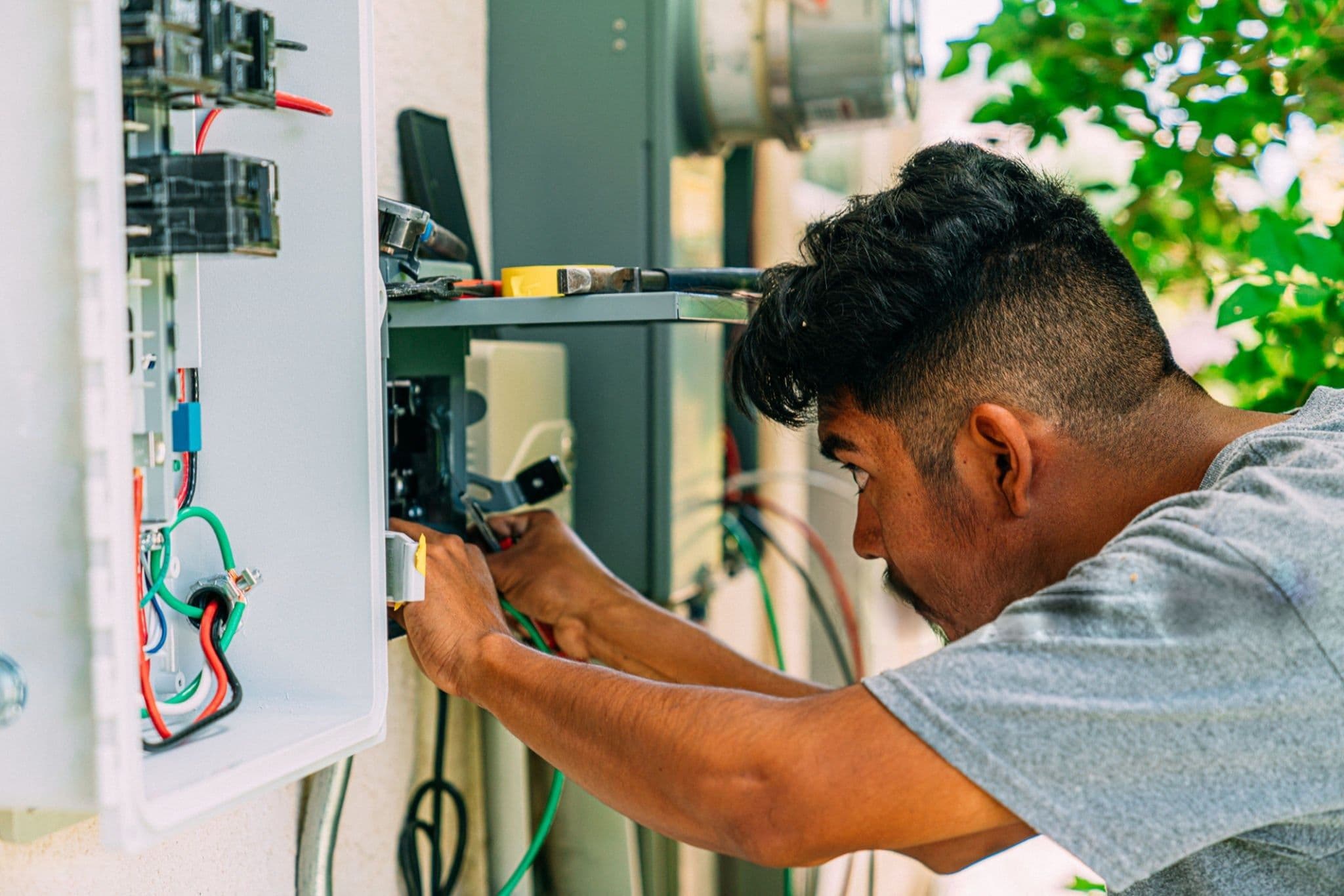 An electrician working on an outdoor residential electrical panel